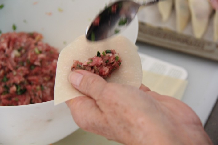 spooning meat onto wonton wrapper