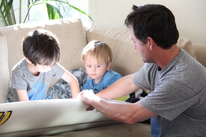 boys putting fins on a new surfboard